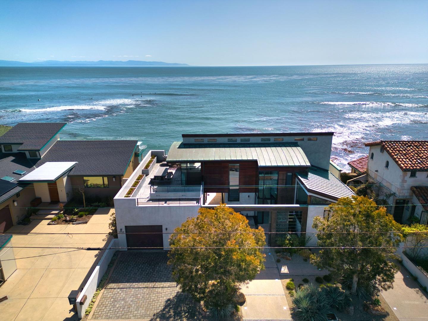 a roof deck with table and chairs next to an ocean