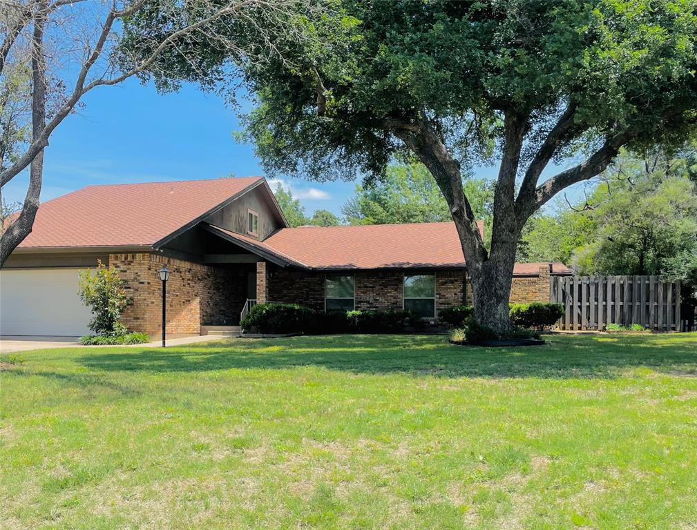 a view of a house with a yard and a large tree