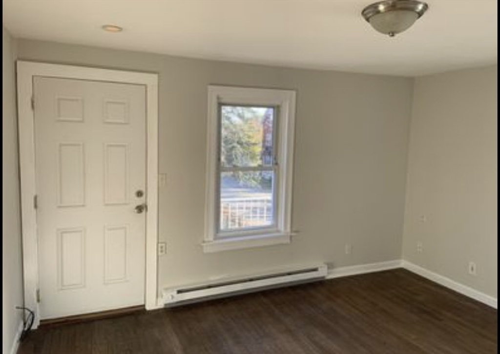 an empty room with wooden floor cabinet and windows