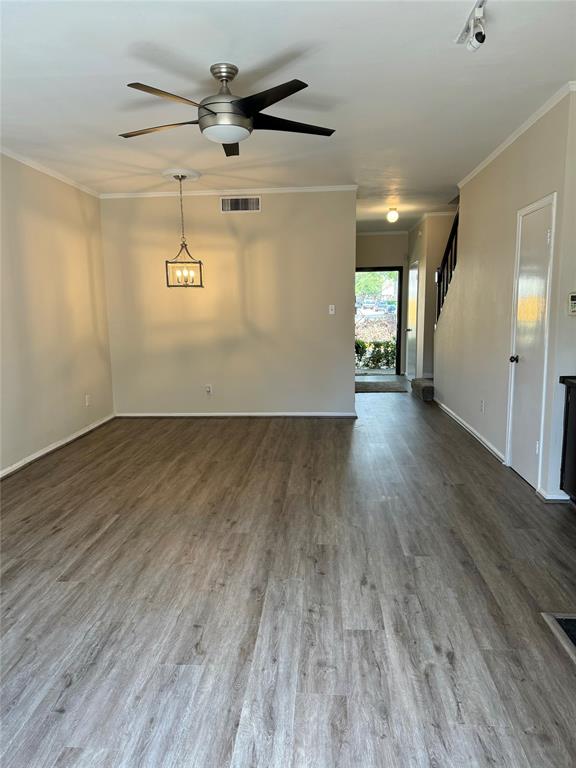 an empty room with wooden floor chandelier fan and windows