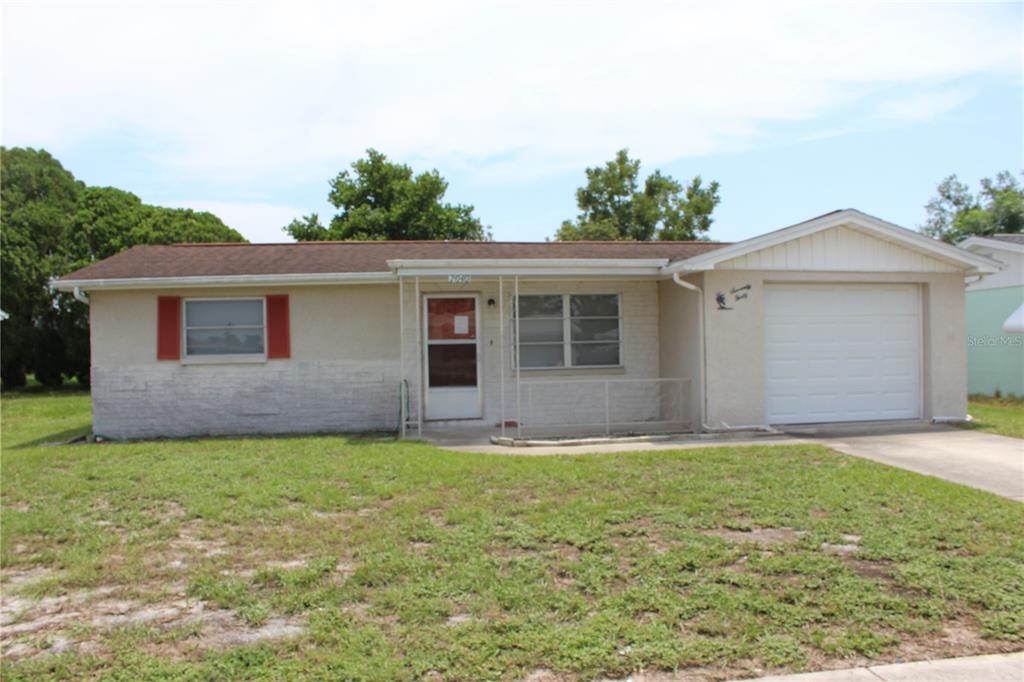 a front view of house with yard and trees in the background