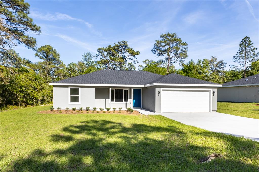 a front view of house with yard and trees in the background