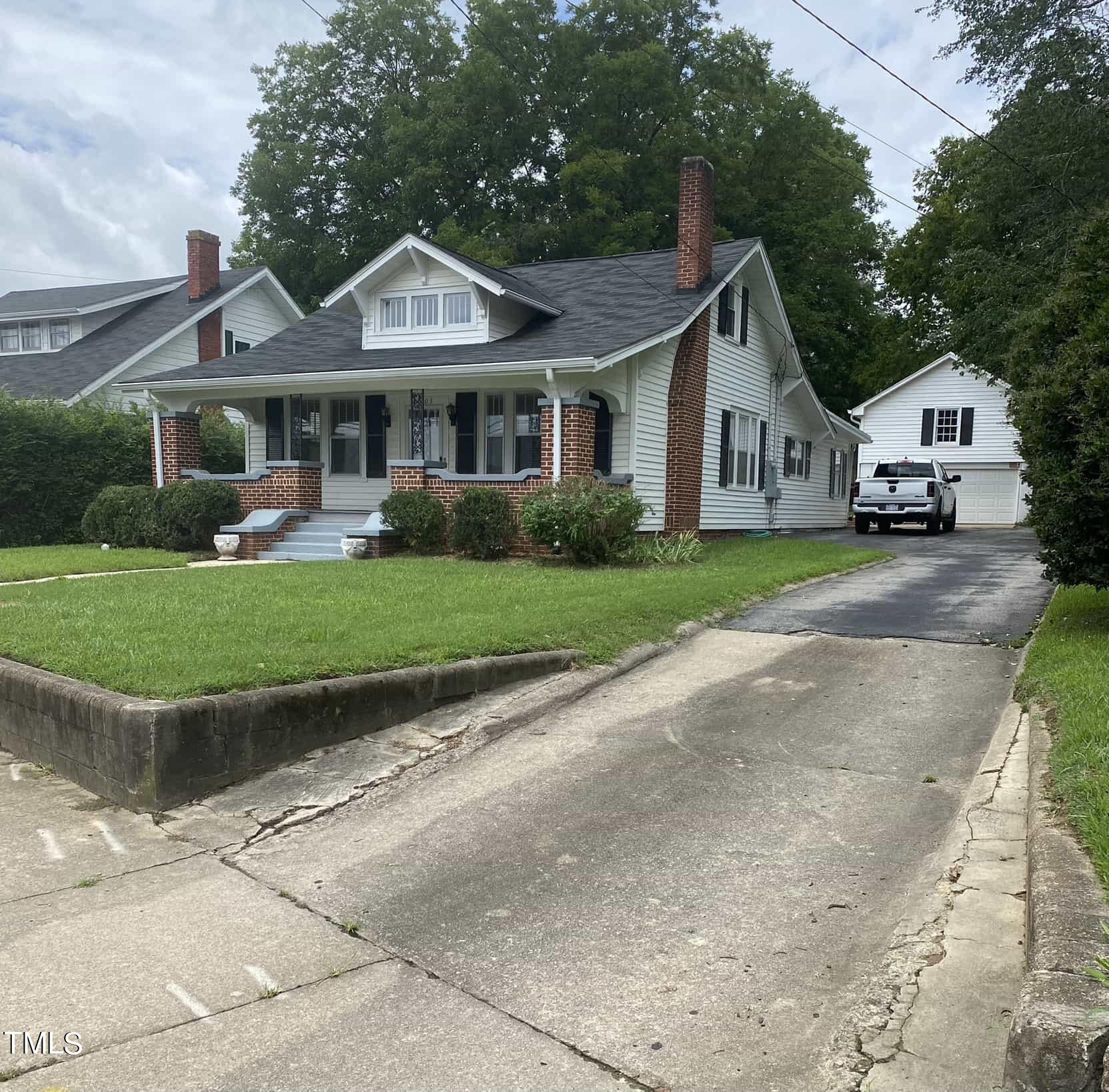 a front view of a house with a garden and trees