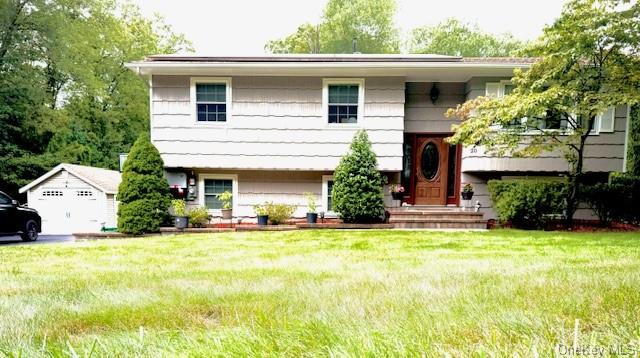 Split foyer home featuring a garage and a front yard