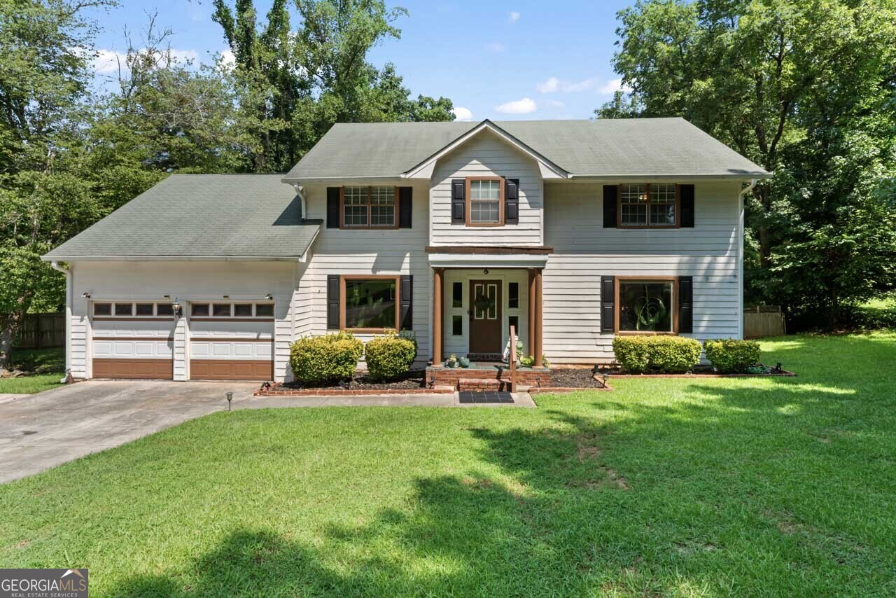 a front view of a house with a yard and green space