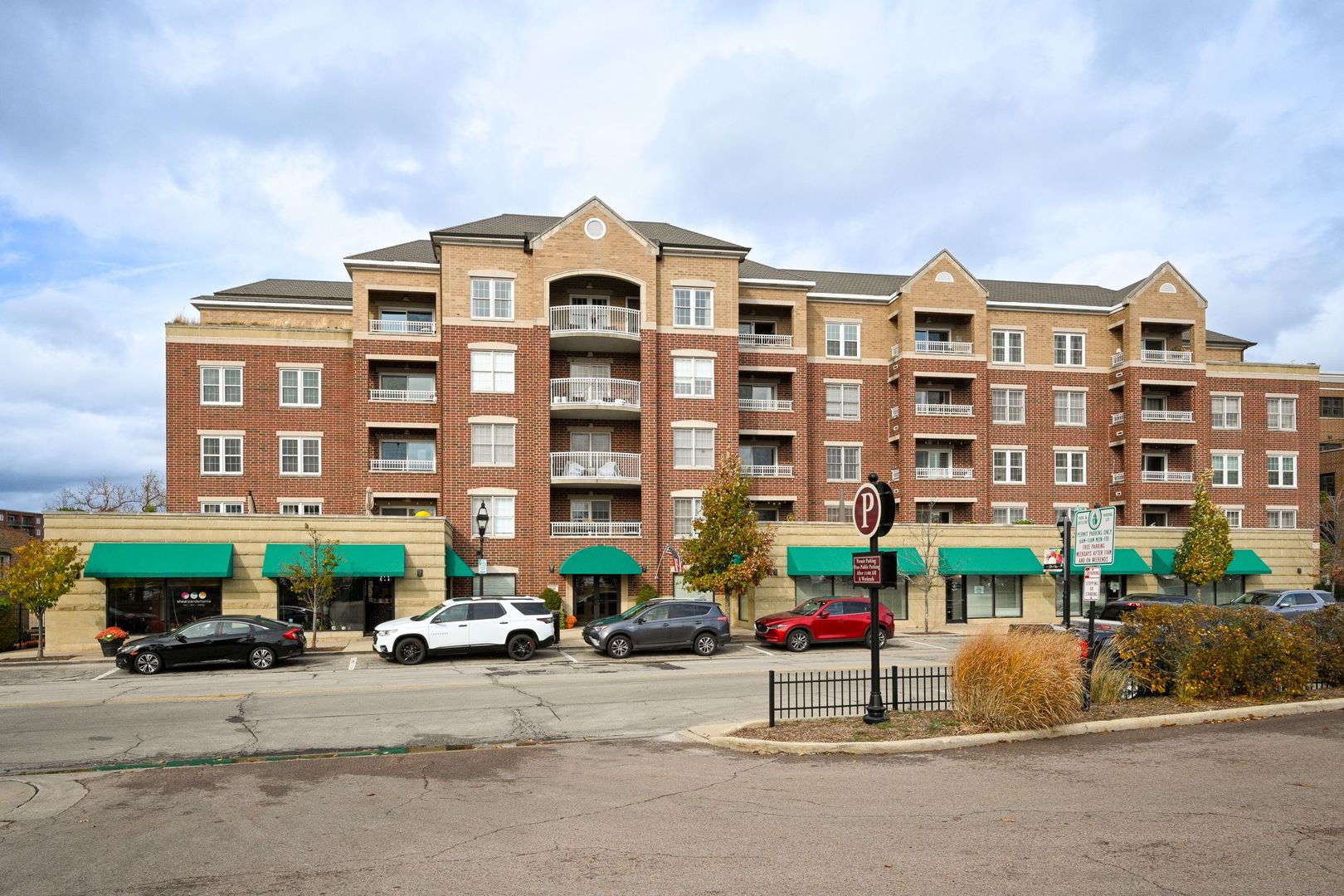 a front view of a building with cars parked