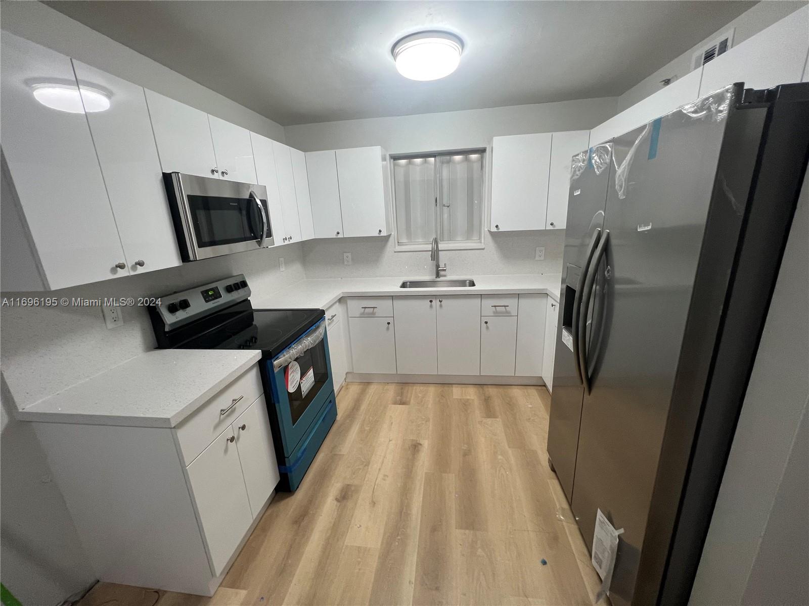 a kitchen with a sink a microwave a refrigerator and cabinets