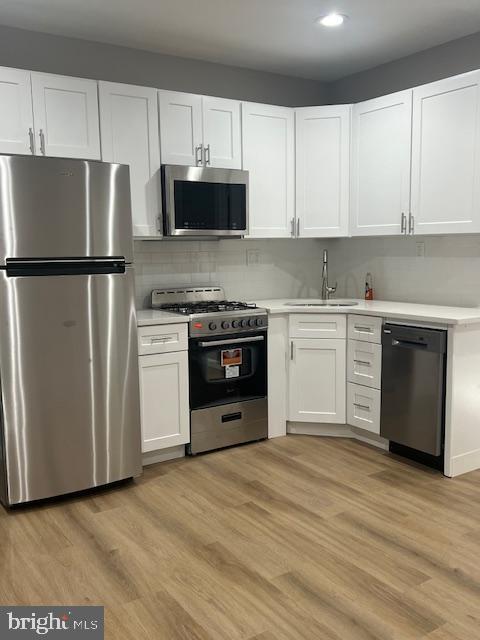 a kitchen with stainless steel appliances granite countertop a refrigerator stove a sink and white cabinets