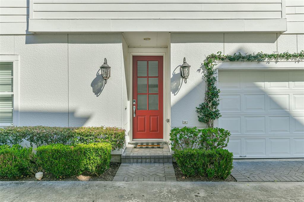 Welcome to this well-maintained townhouse! The modern white exterior is accentd by a charming red front door that is flanked by classic wall lanterns.