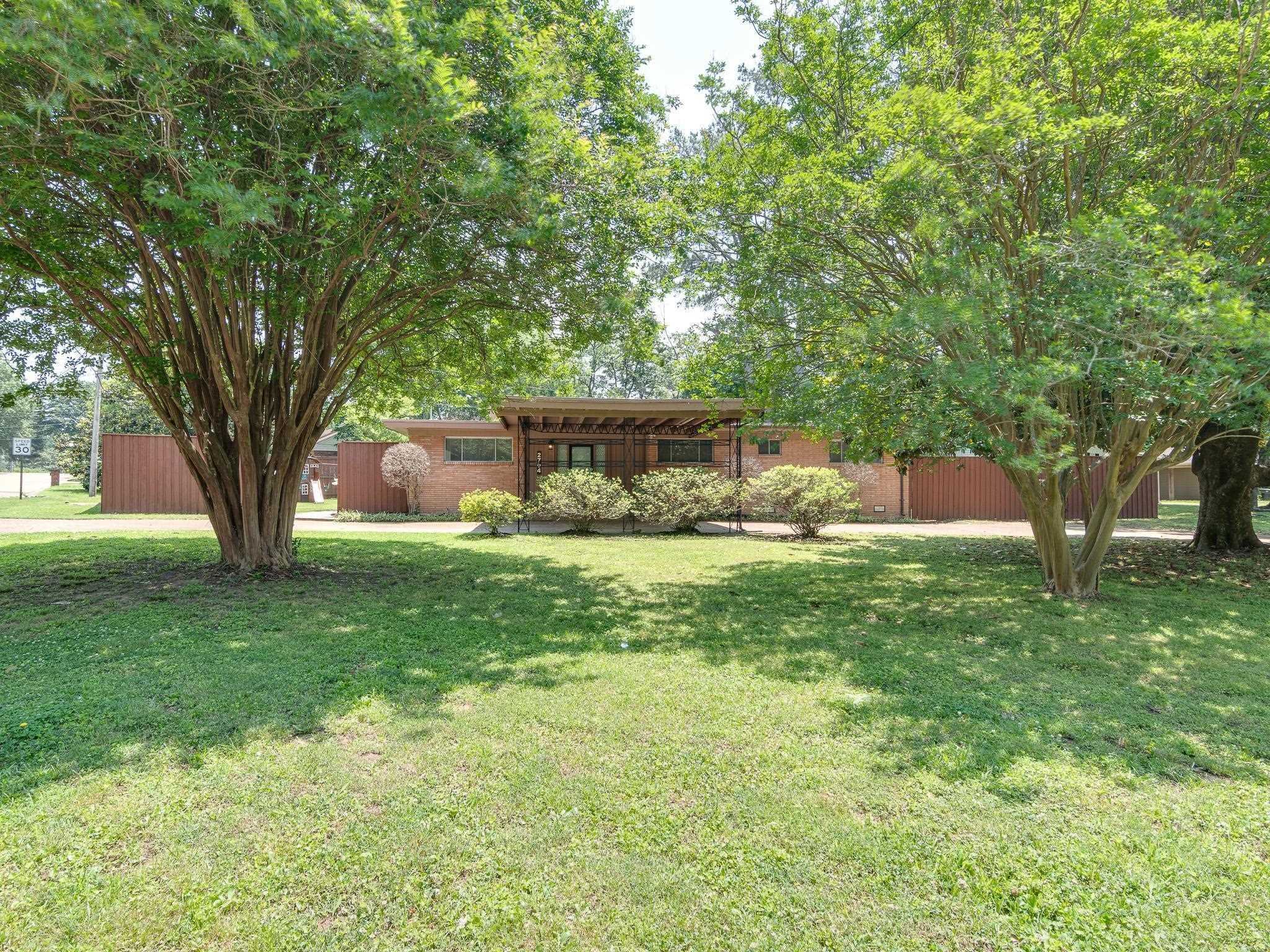 a view of backyard with large trees and a barn