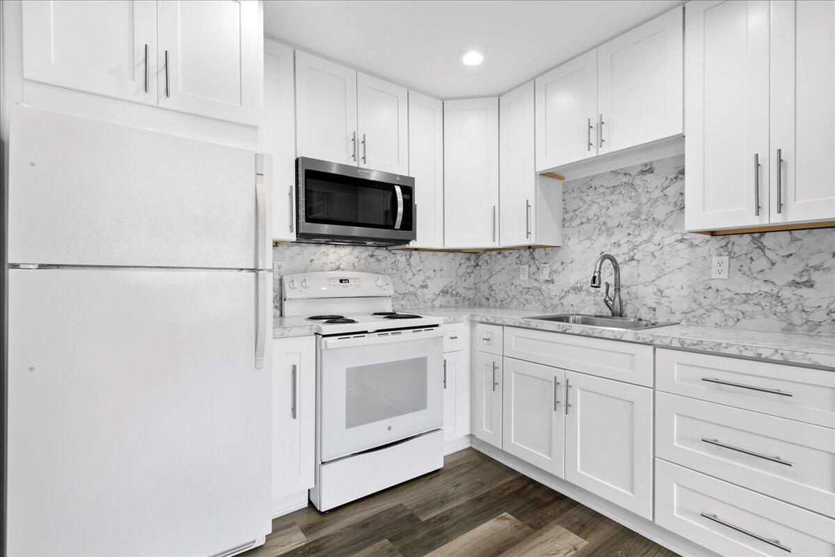 a kitchen with granite countertop white cabinets and white appliances