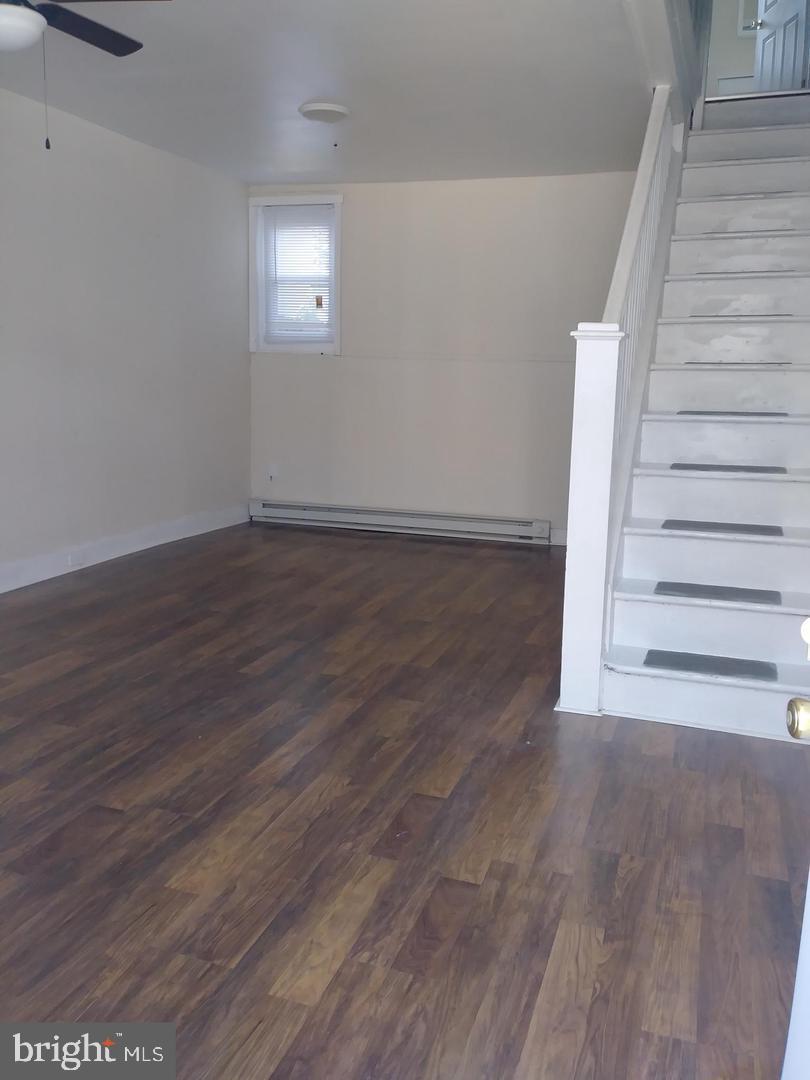 a view of an empty room with wooden floor and stairs