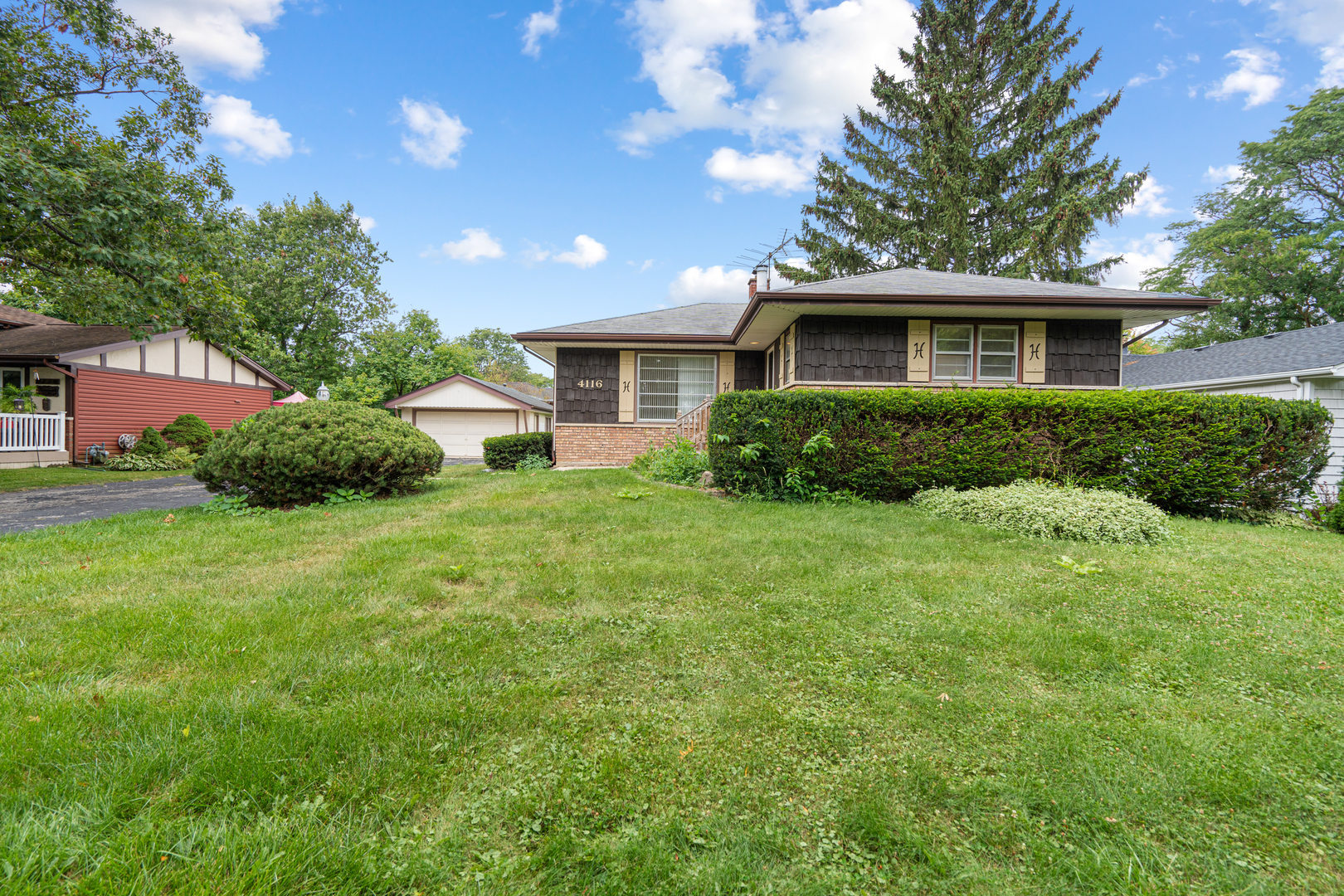 a front view of a house with a yard and trees