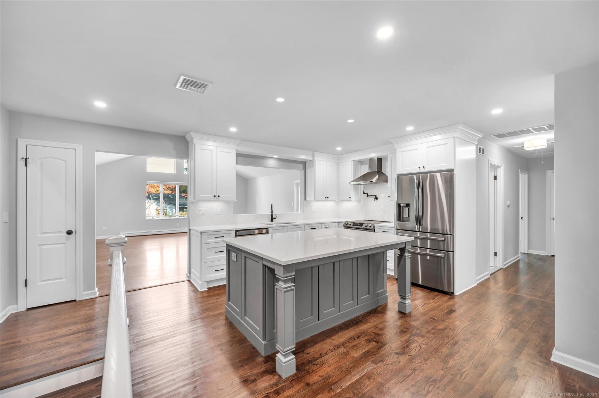 a large kitchen with stainless steel appliances granite countertop a large counter top and wooden floors