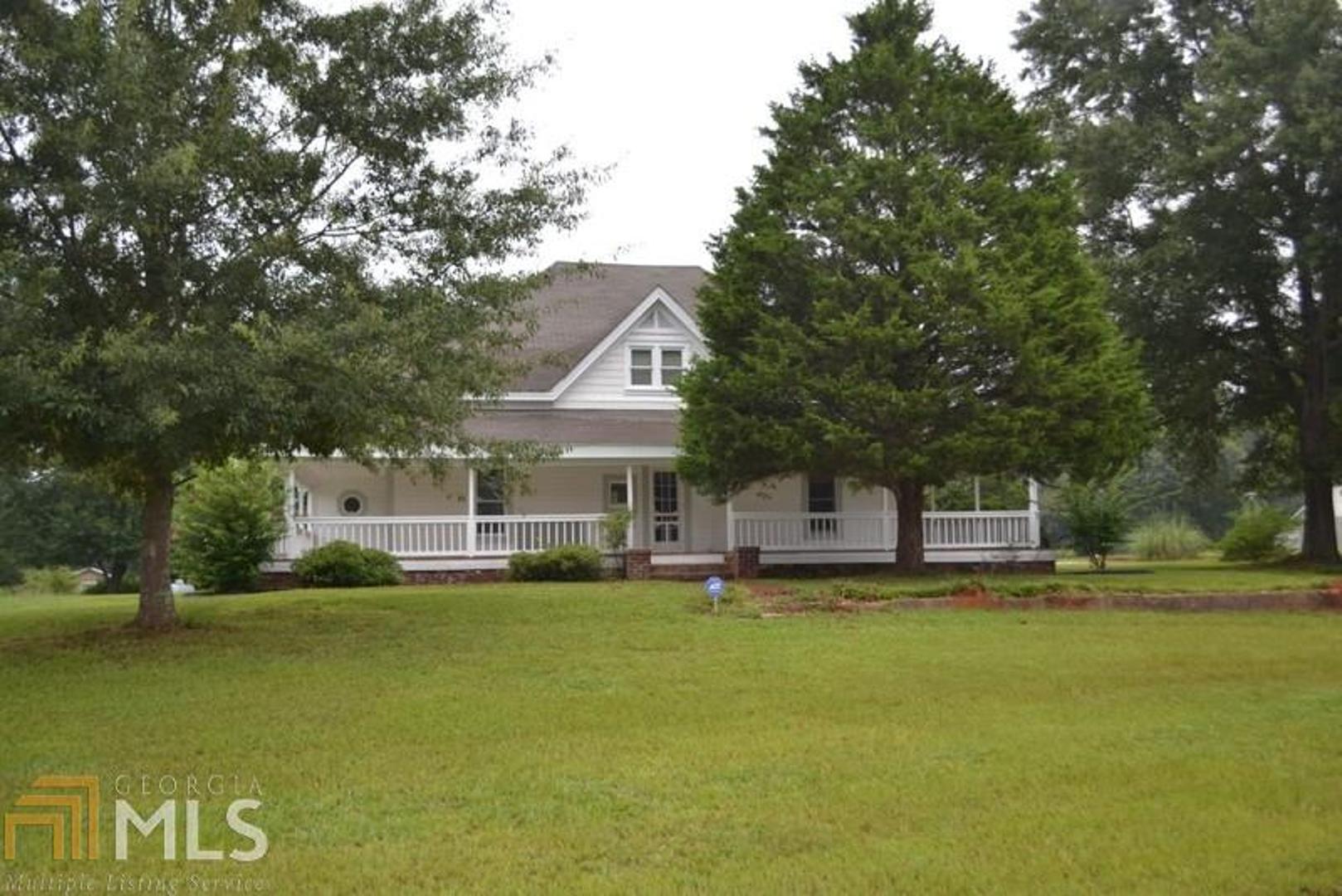 a view of a house with a big yard and large trees