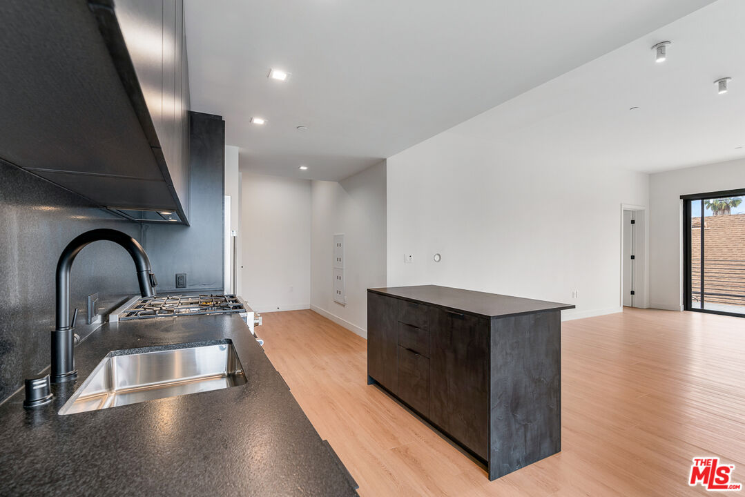 a kitchen with stainless steel appliances granite countertop a sink a stove and a wooden floors