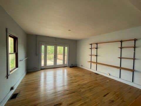 a view of an empty room with a window and wooden floor