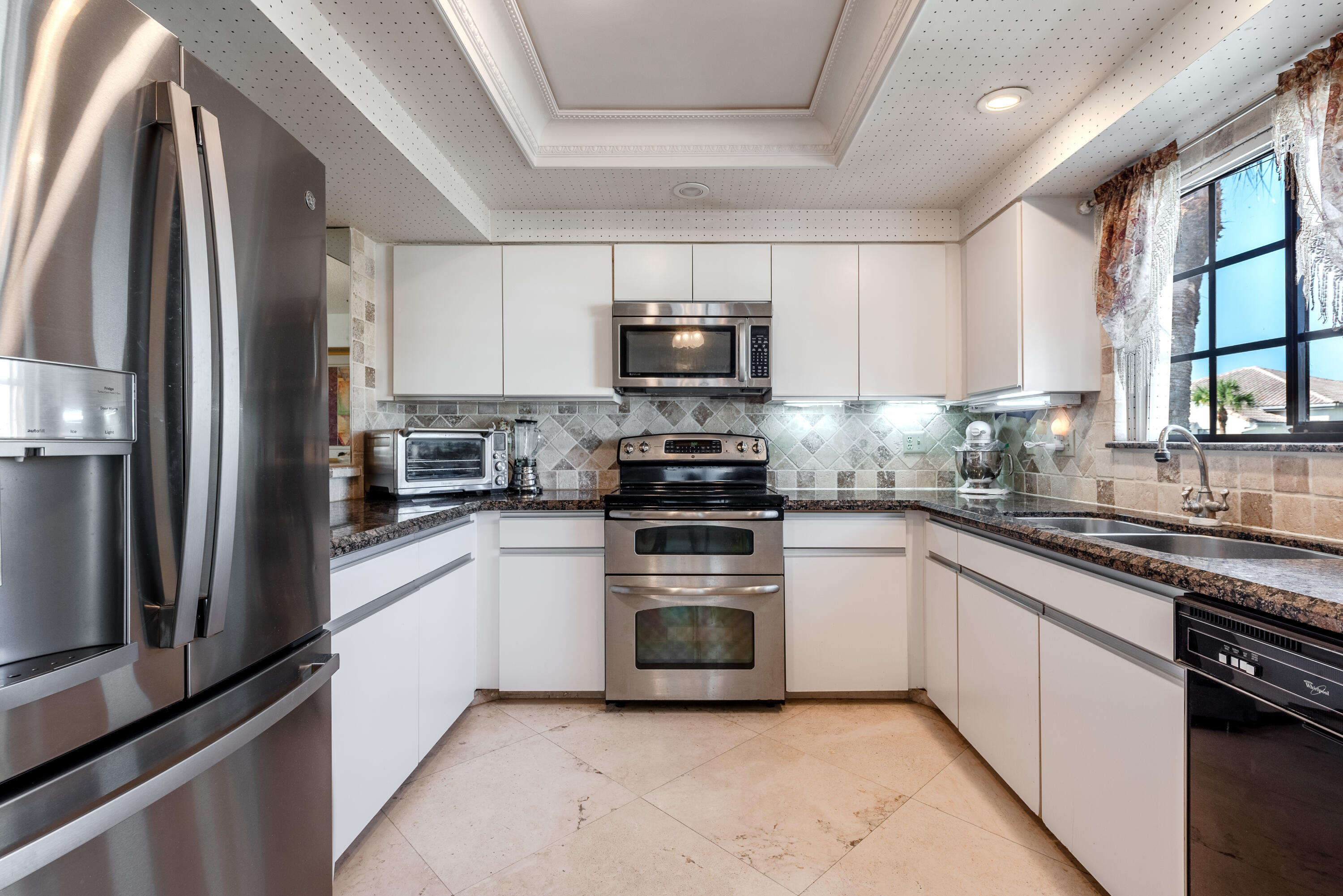 a kitchen with granite countertop a refrigerator and a stove top oven