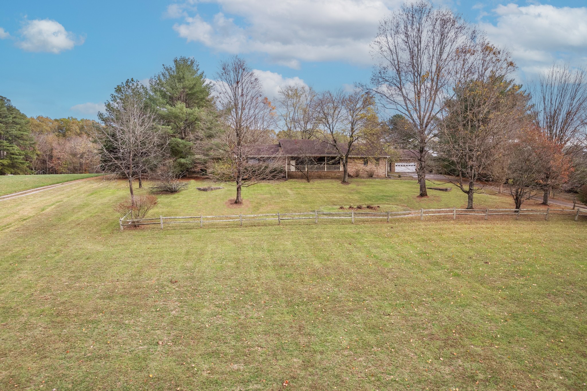 Cleared lawn with mature trees and garden accents.  Front yard has wood fence to distinguish it from the front pasture.