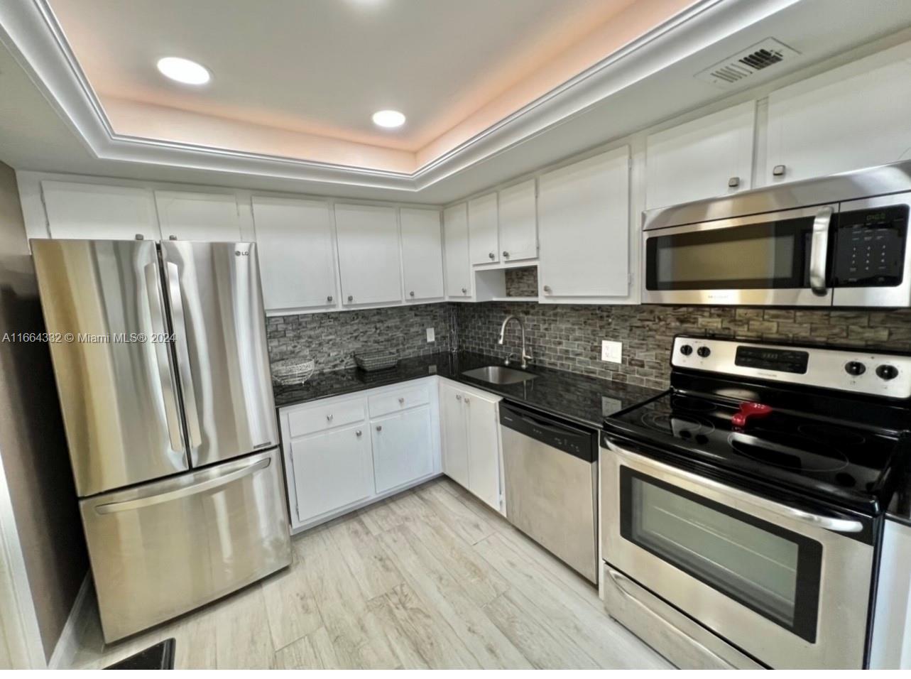 a kitchen with granite countertop a refrigerator stove and microwave