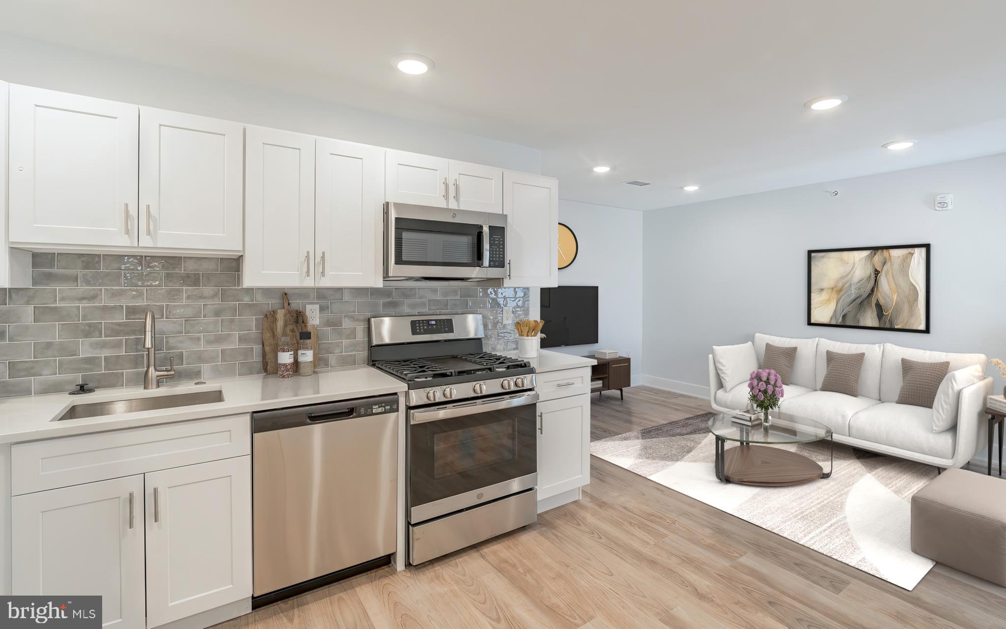 a kitchen with white cabinets a sink stove and microwave oven with wooden floor