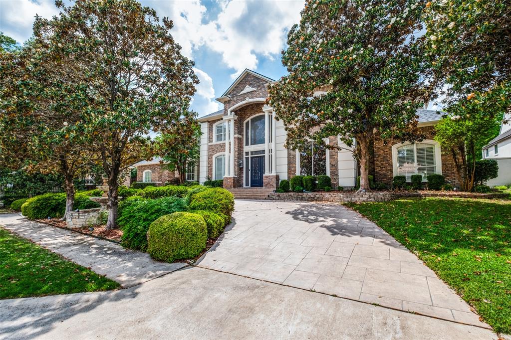 a view of a brick house with a big yard and large trees