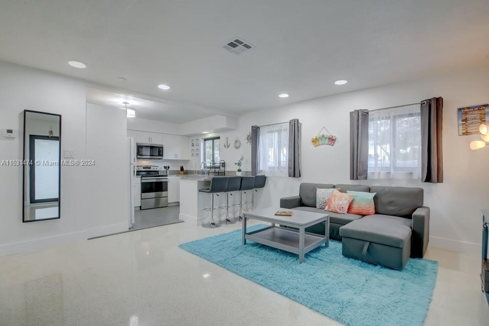 a living room with furniture and view of kitchen