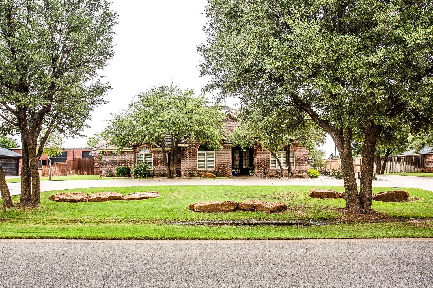 a front view of a house with a yard and an trees