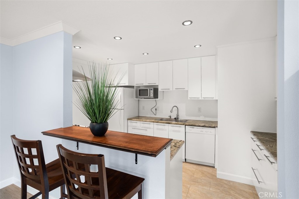 a kitchen with stainless steel appliances kitchen island a table chairs in it and white cabinets