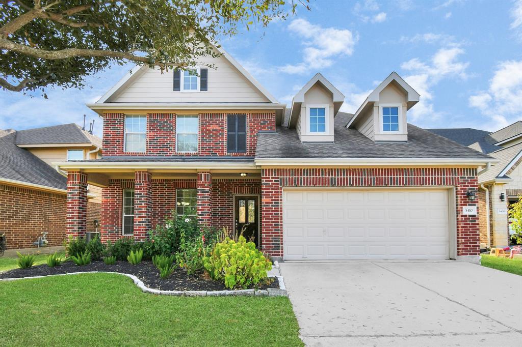 Discover this charming two-story brick residence, boasting a classic pitched roof with inviting dormer windows, a spacious two-car garage, and a beautifully landscaped front yard.