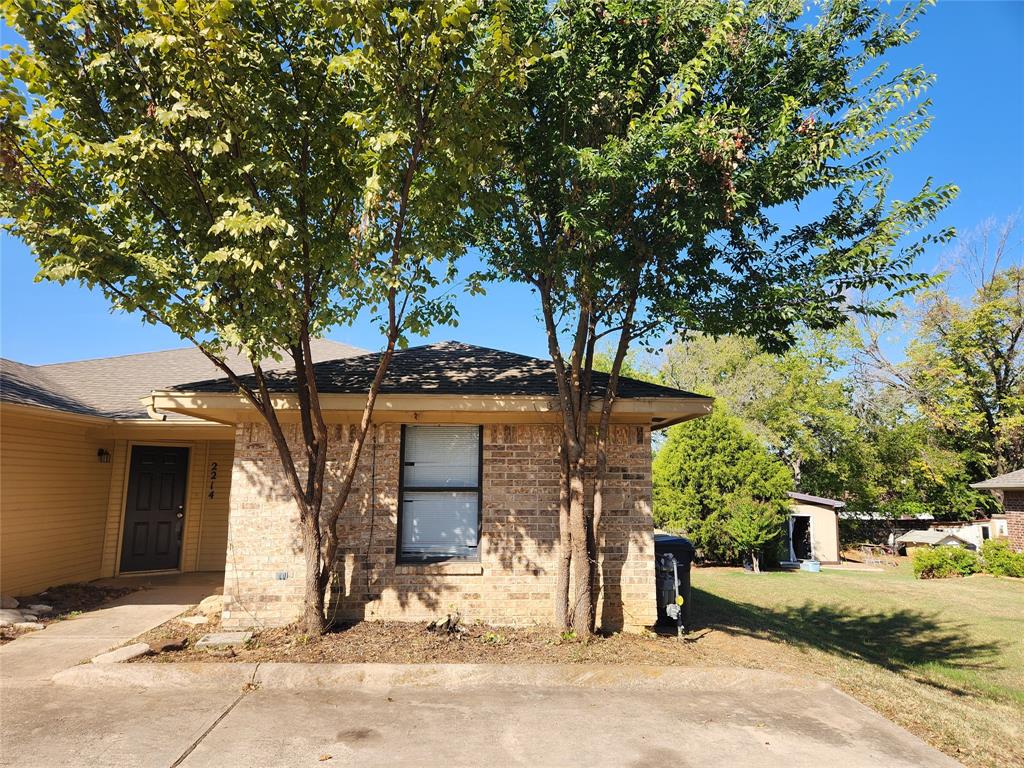 a front view of a house with a tree