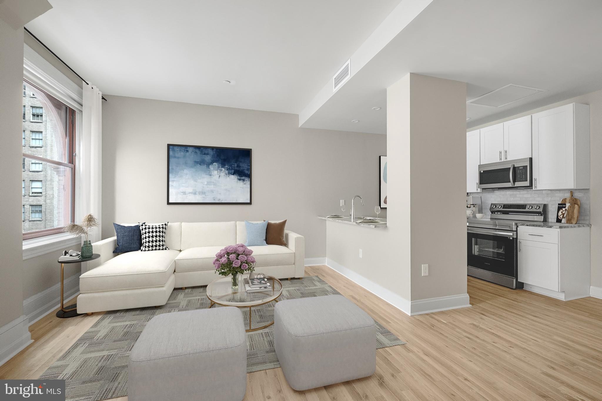 a living room with furniture white walls and kitchen view