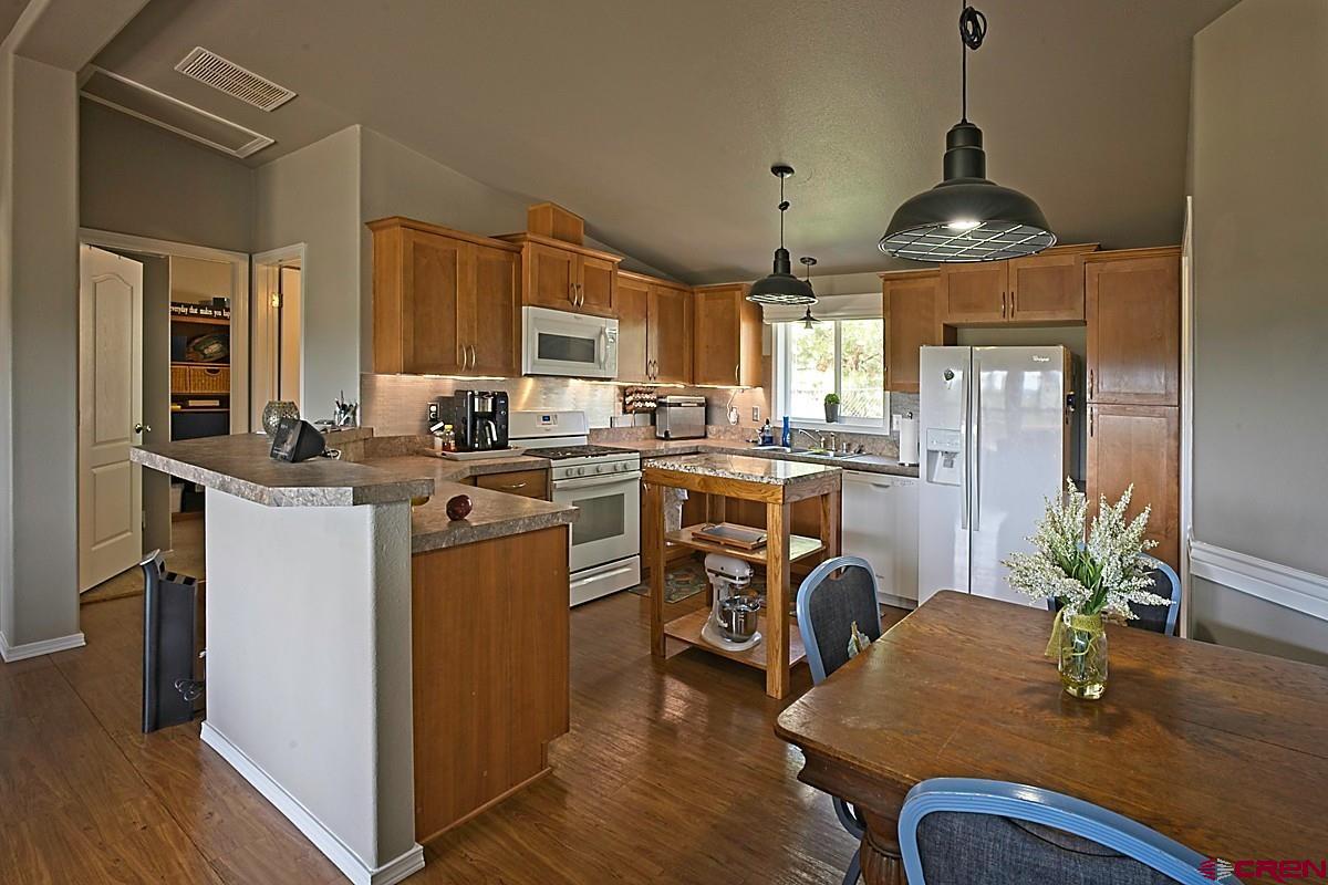 a kitchen with stainless steel appliances granite countertop a stove top oven a sink dishwasher a dining table and chairs with wooden floor