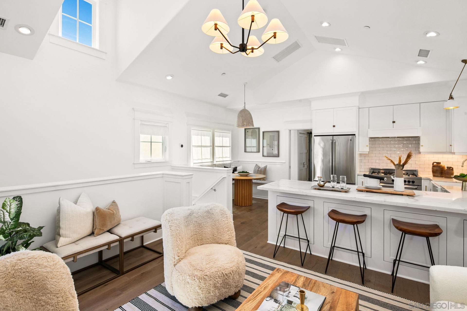 a living room with furniture kitchen view and a large window