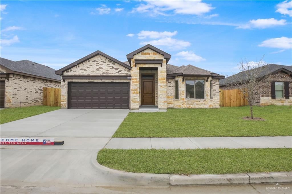 View of front of property featuring a garage and a front lawn