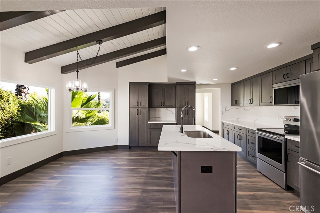 a kitchen with stainless steel appliances granite countertop a sink a stove and a wooden floors