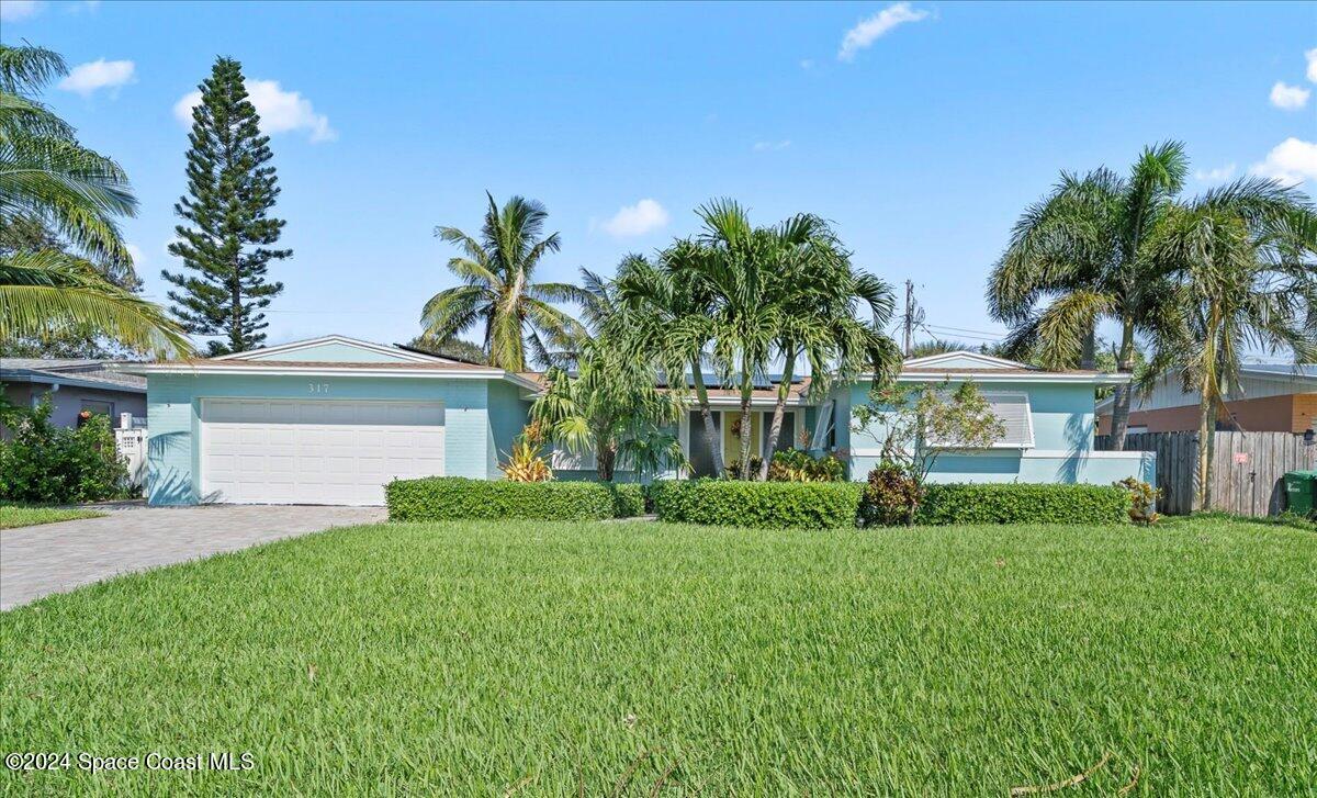 a front view of a house with a garden and palm trees