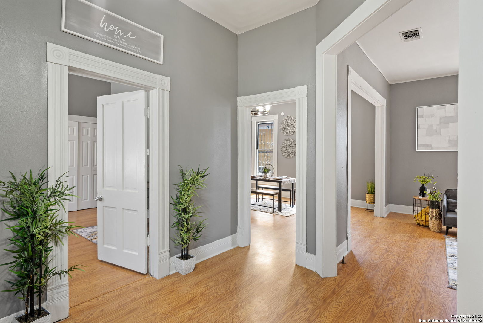 a view of a hallway with wooden floor and a livingroom with furniture