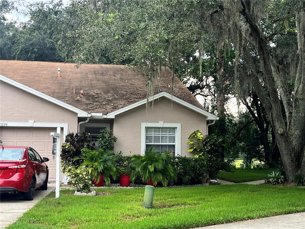 a house that is sitting in front of a big yard with potted plants