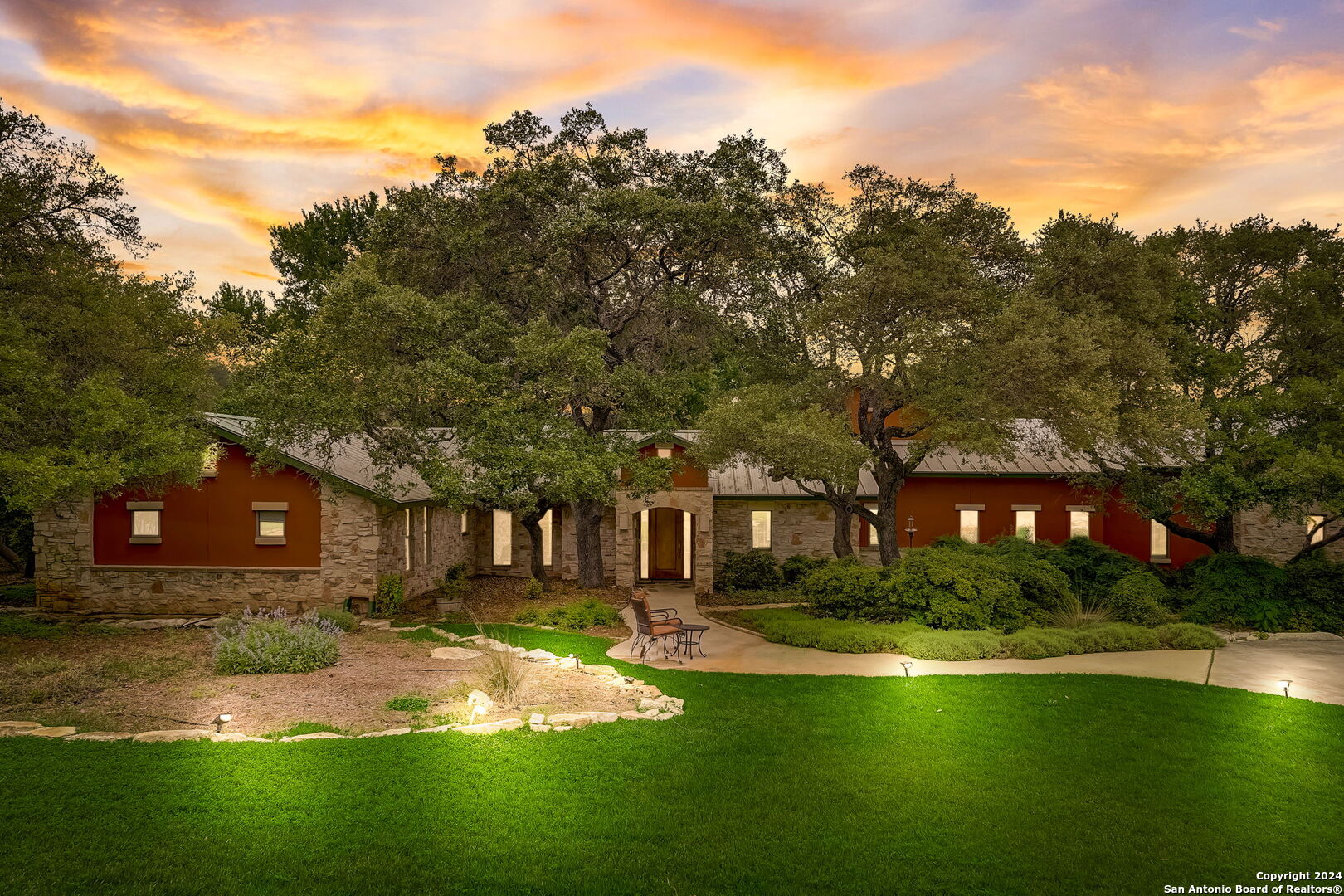 a front view of a house with garden and trees