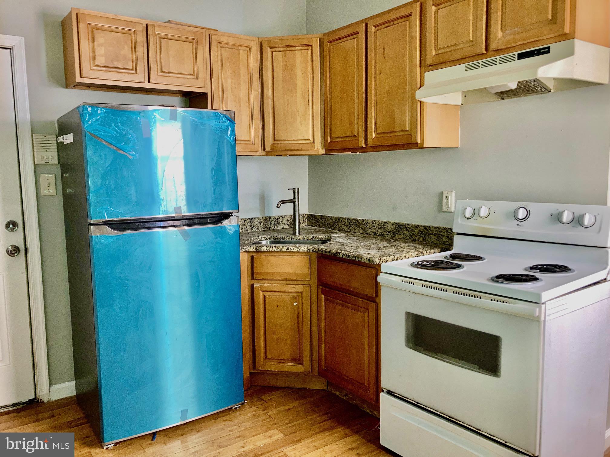 a kitchen with a stove top oven and refrigerator