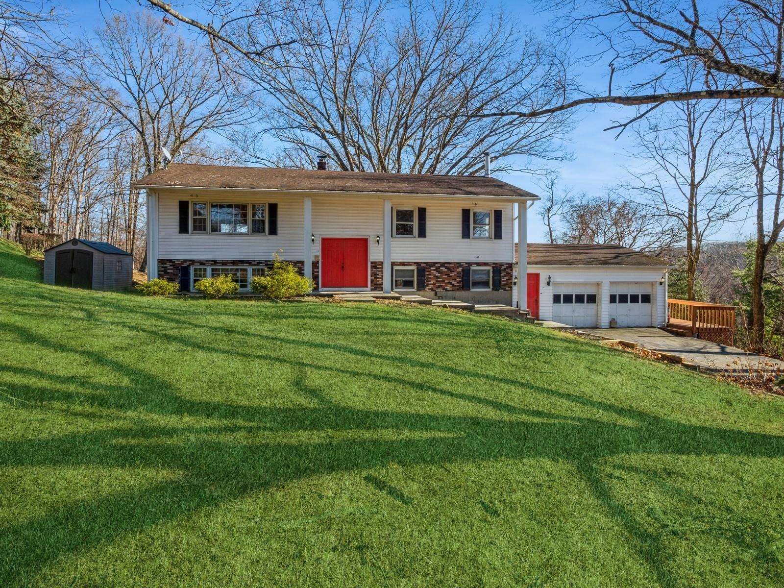 Raised ranch with a front yard and a storage unit