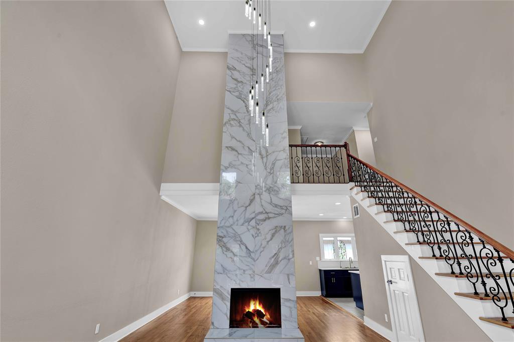 Living room features a 2 story floor to ceiling porcelain tiled fireplace and beautiful chandelier