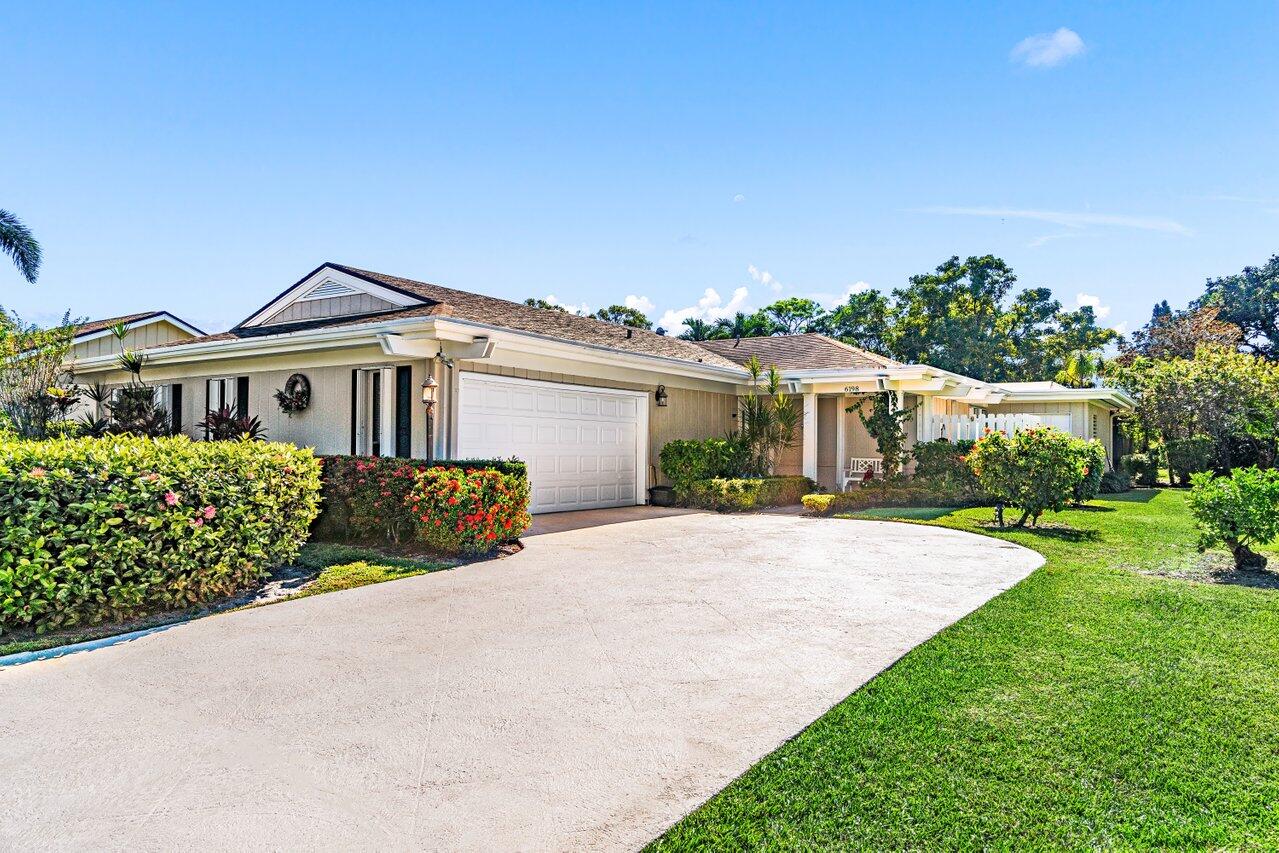 a front view of a house with a yard and potted plants