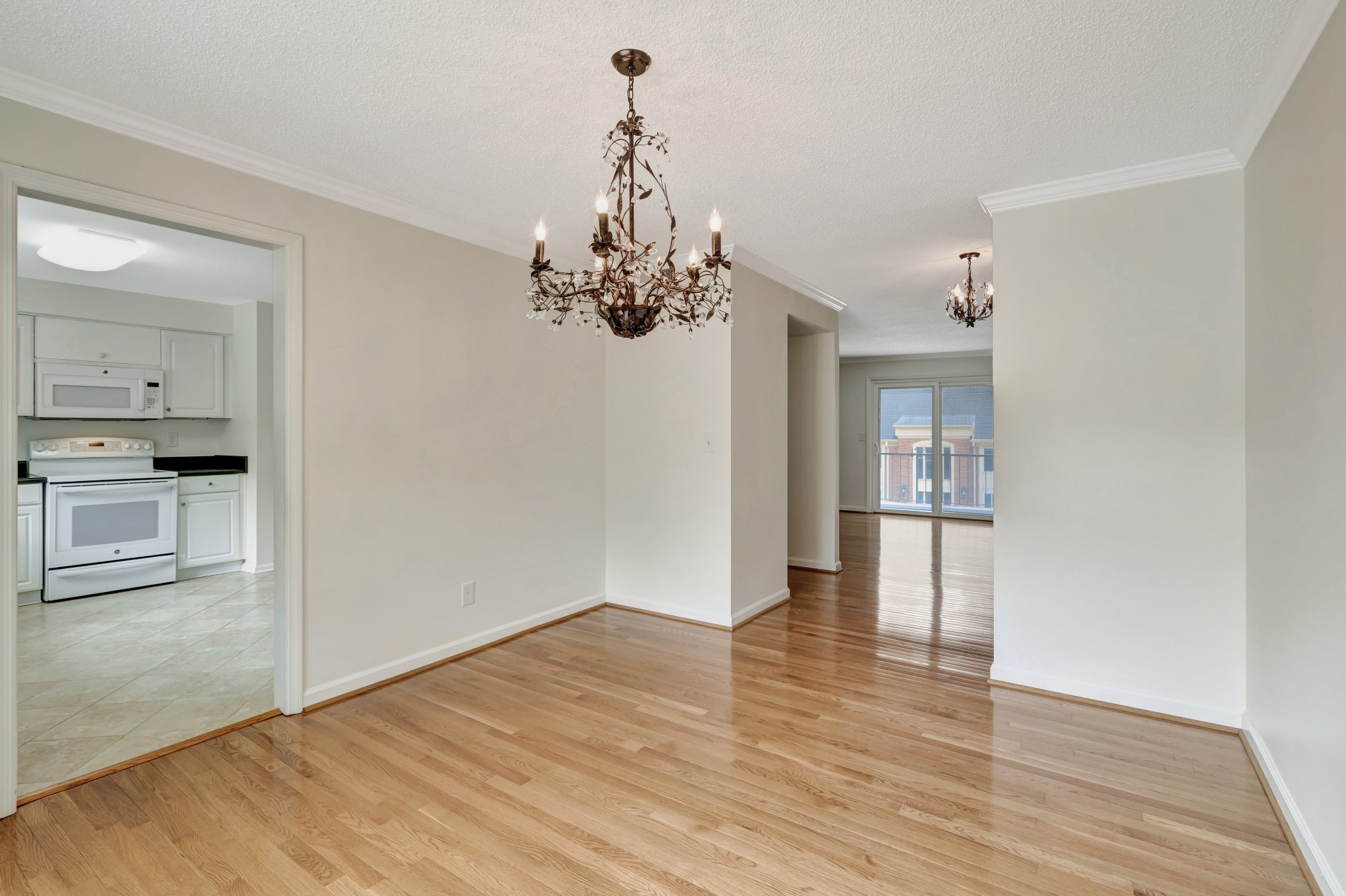 a view of a hallway with wooden floor and a kitchen