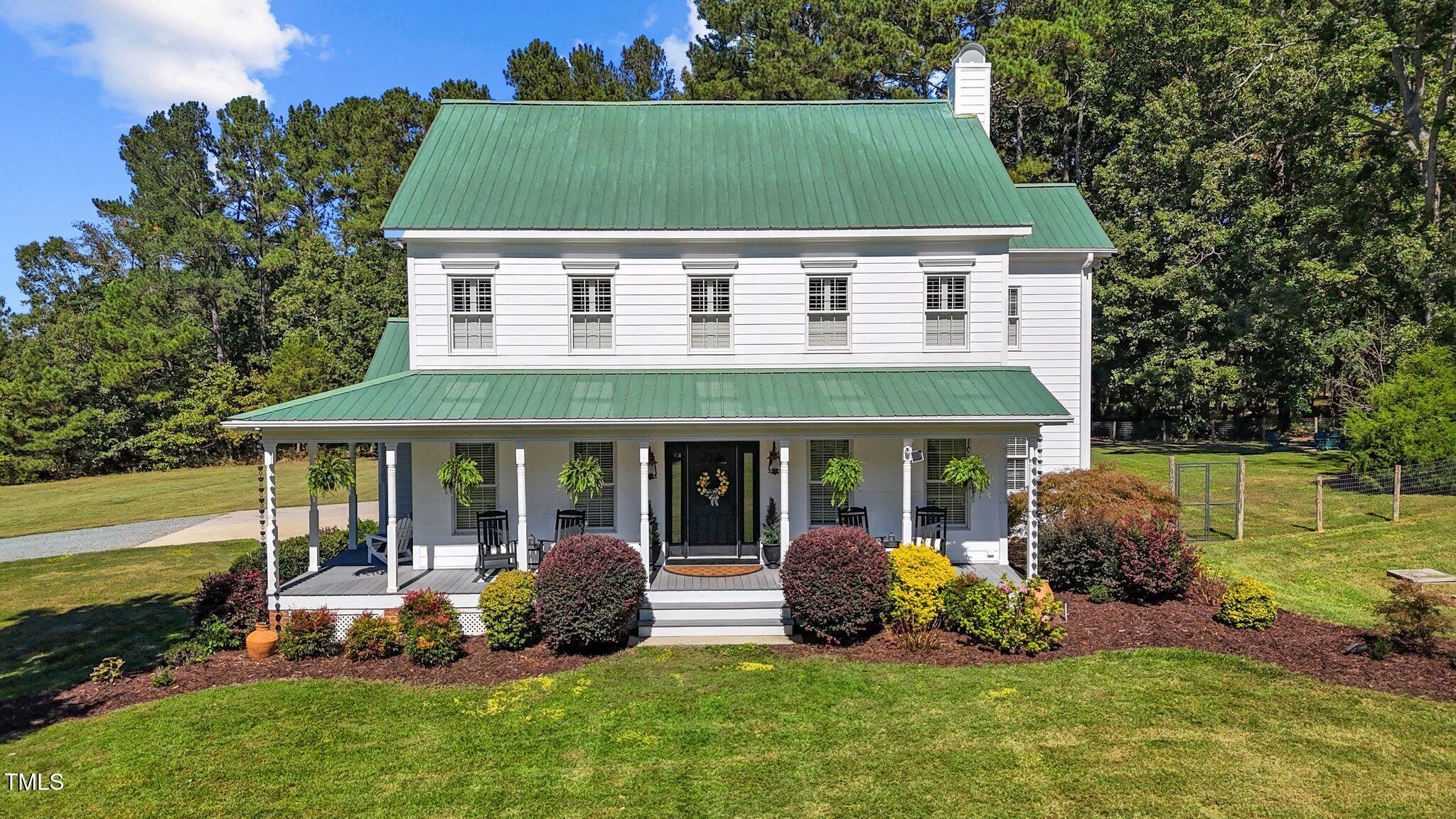 a view of a white house with a big yard and potted plants