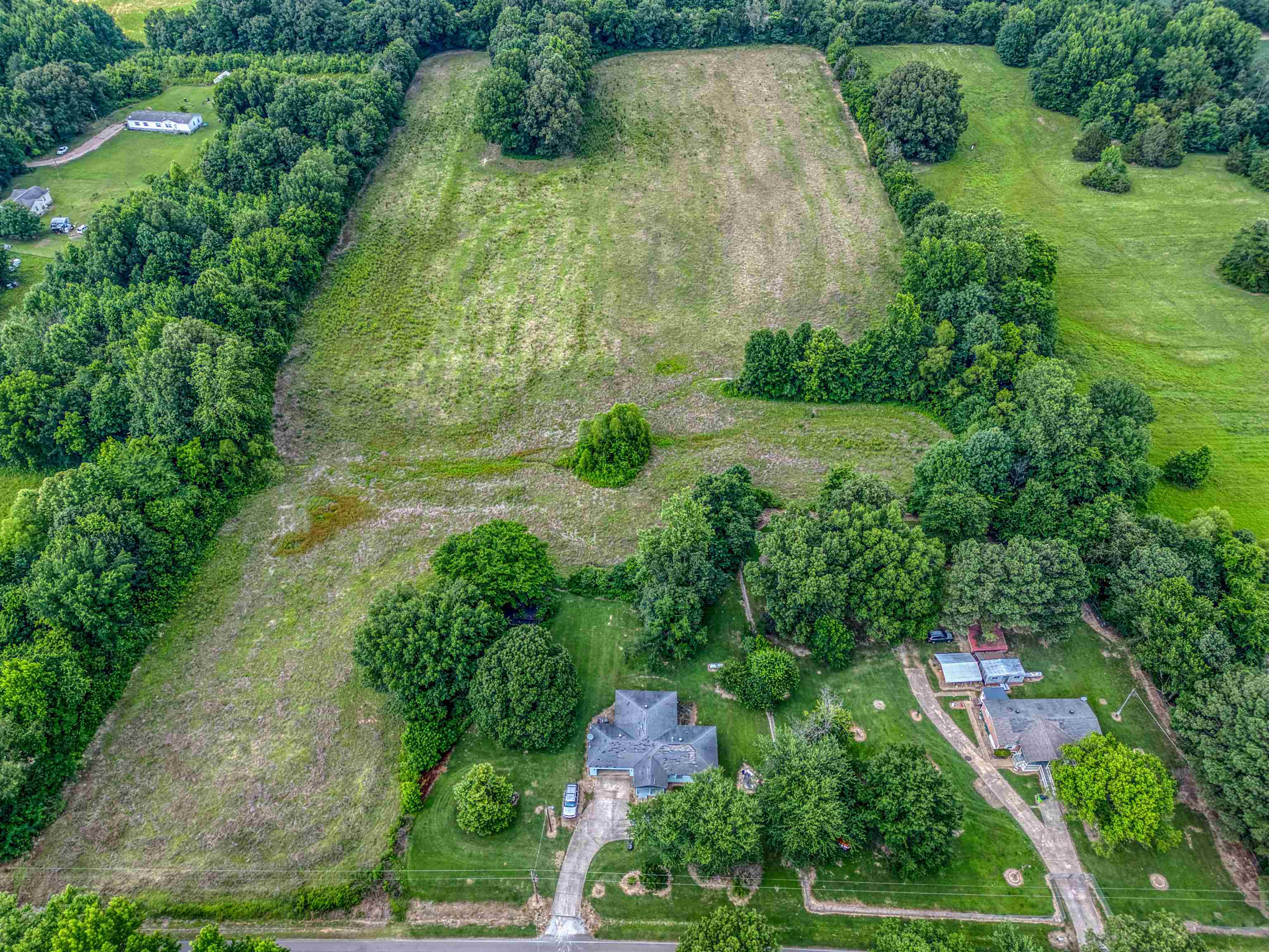 an aerial view of residential house with outdoor space and trees all around