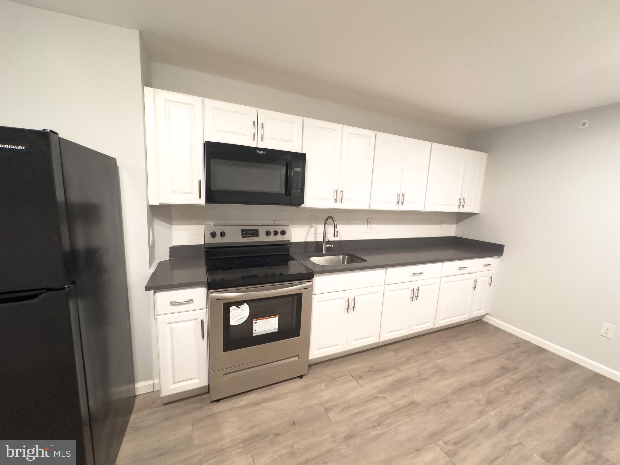 a kitchen with granite countertop a refrigerator stove and microwave