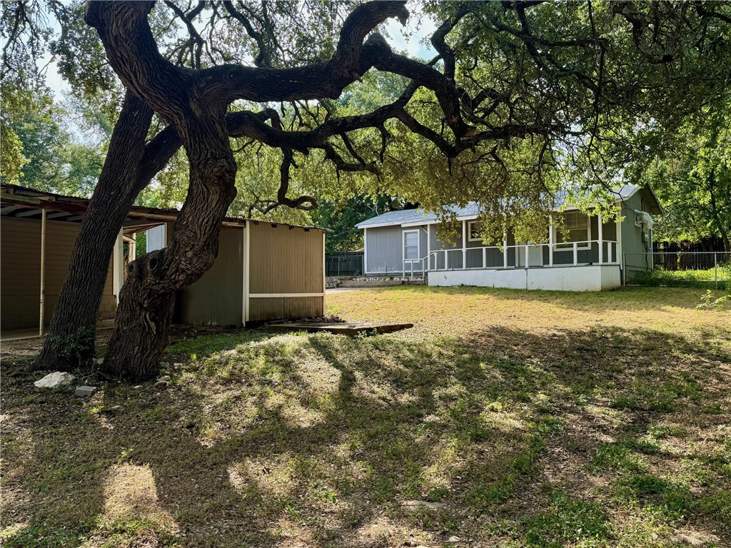 a view of a house with a yard and a large tree