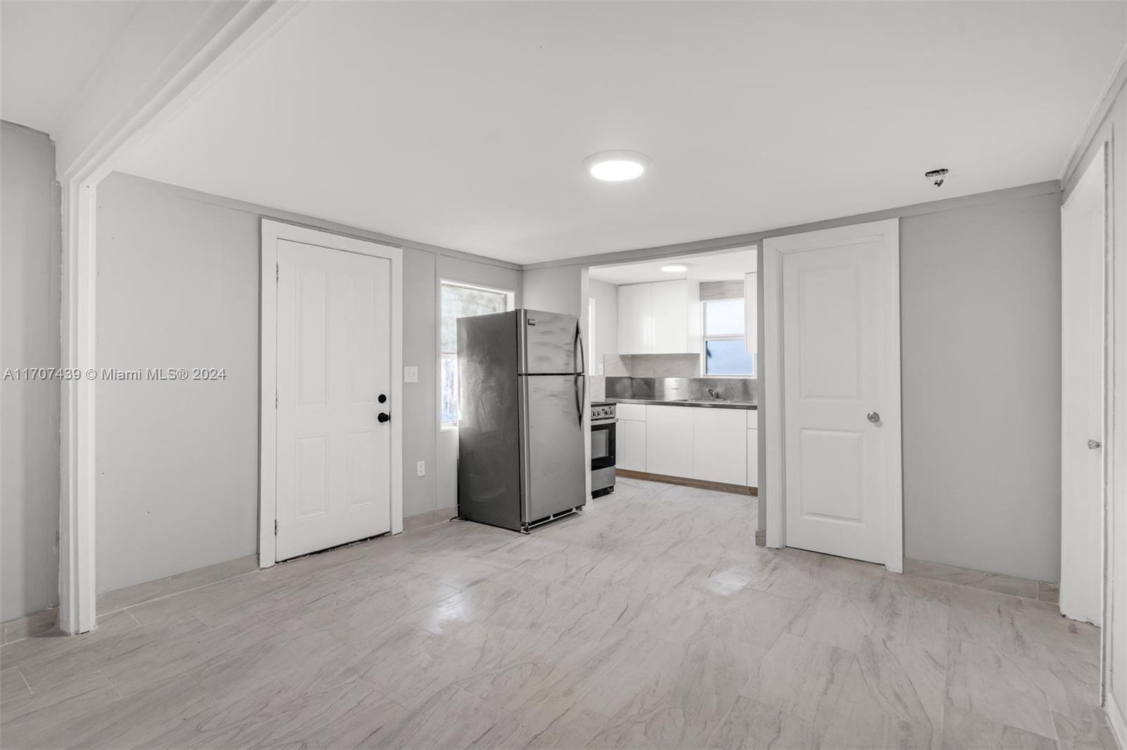 a view of a kitchen with refrigerator and wooden floor